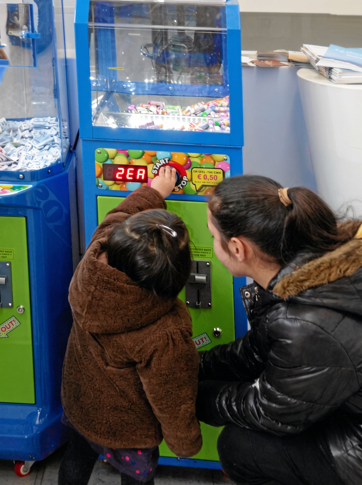 Kind und Begleitperson am Süßwarenautomaten